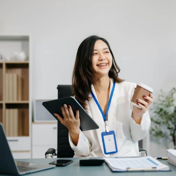Asian Businesswoman Analyzing Finance on Tablet and Laptop at modern Office Desk