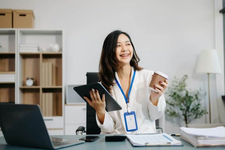Asian Businesswoman Analyzing Finance on Tablet and Laptop at modern Office Desk