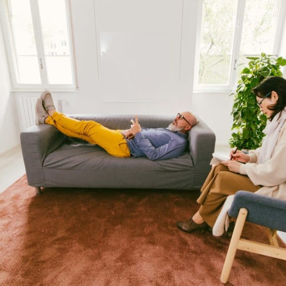 man in therapy at psychologist lying on couch