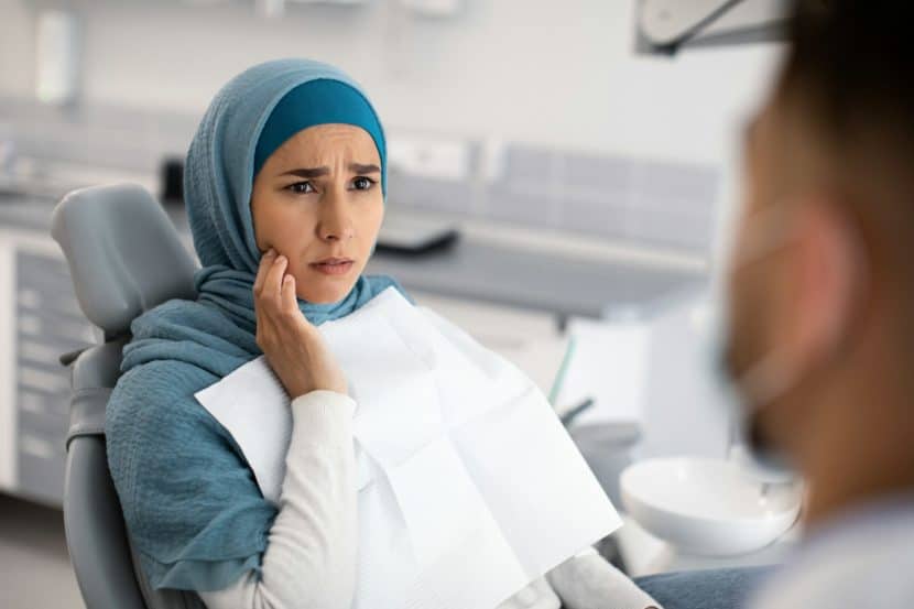 Dentists warn patients to stop using this popular product ASAP Teeth Problems. Muslim Female In Dentist Chair Showing Aching Tooth To Doctor